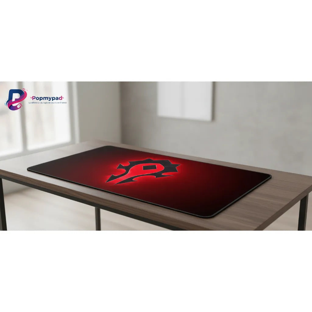 Tapis de souris World of Warcraft - Édition Horde Incandescente sur un bureau, avec le logo de la Horde sur fond rouge.