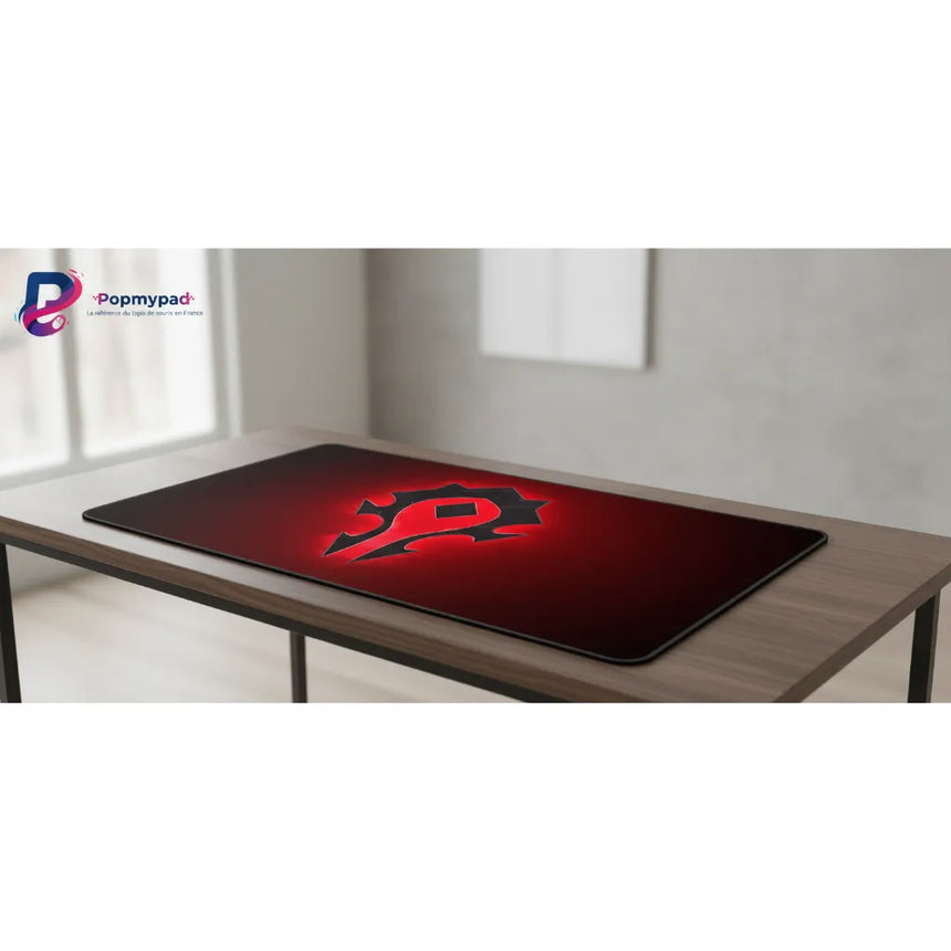 Tapis de souris World of Warcraft - Édition Horde Incandescente sur un bureau, avec le logo de la Horde sur fond rouge.